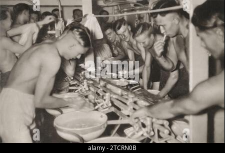 Sur cette image, des Marines allemands, qui font partie de la Kriegsmarine, sont vus effectuant leurs routines quotidiennes de lavage et de brossage des dents. La photographie met en évidence les conditions à bord des navires de la Seconde Guerre mondiale, où l'espace était souvent limité, mais la propreté et l'hygiène personnelle étaient maintenues avec une précision militaire. T Banque D'Images