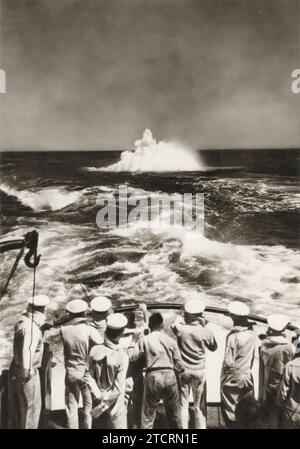 Sur cette image, les Marines allemands de la Kriegsmarine, stationnés vers l'arrière de leur navire, observent intensément une détonation de mine marine dans les vagues. Cet exercice de formation, qui comprenait l ' observation des explosions de mines, était crucial pour familiariser les marines avec les effets et les dangers des mines navales. Comprendre la mécanique et l'impact de ces explosifs était vital pour leur préparation opérationnelle, en particulier dans les eaux chargées de mines qui étaient courantes pendant la Seconde Guerre mondiale Banque D'Images