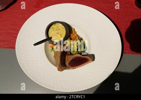 Steak de thon à la sauce bearnaise sur assiette blanche : île de Noirmoutier, Vendée, France. Banque D'Images