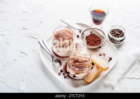 Dessert italien traditionnel tiramisu dans une tasse de verre. Tiramisu fait maison dans une tasse en verre, processus de cuisson étape par étape. Dessert italien traditionnel non cuit Banque D'Images