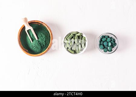 Trois récipients avec différents types de poudre naturelle de spiruline, capsules, comprimés sur fond blanc. Detox. Multivitamine. super-aliment Banque D'Images