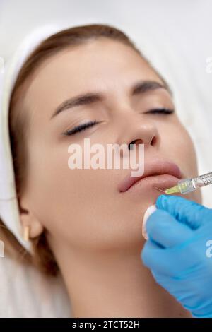 cosmétologue fait des injections pour agrandir les lèvres d'une belle femme. Injection de mastic pour lèvres Banque D'Images