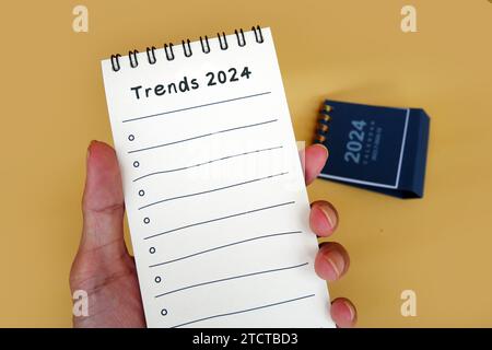 Bloc-notes à main avec texte tendances 2024. Nouvelle année, nouvelles solutions et idées, concept. Banque D'Images