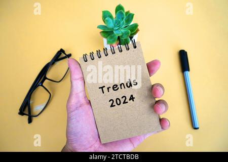 Bloc-notes à main avec texte tendances 2024. Nouvelle année, nouvelles solutions et idées, concept. Banque D'Images