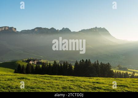 Paysage rural dans la région d'Appenzell avec des fermes et des prairies dans la dernière lumière du soleil du soir, vue sur les montagnes Alpstein avec Saentis Banque D'Images