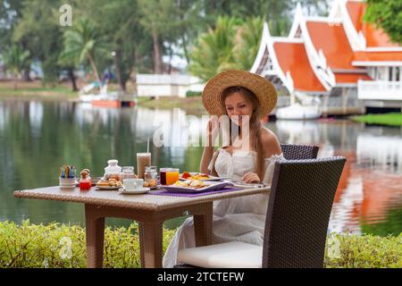 Femme appréciant le petit déjeuner à l'extérieur avec vue sur le lac Banque D'Images