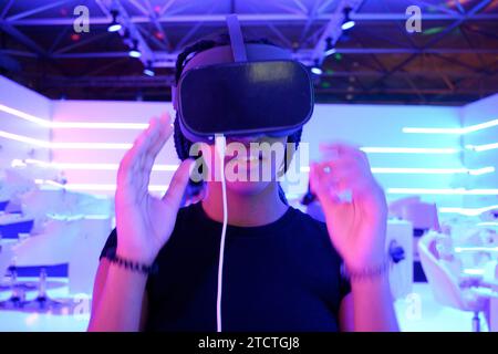 Fille avec tresses portant des lunettes de réalité virtuelle VR avec fond de lumières de néon horizontal Banque D'Images
