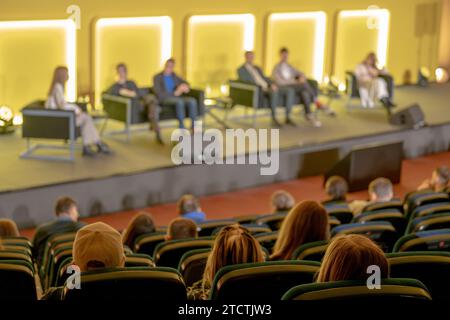 Vue en grand angle des réalisateurs donnant une présentation à divers hommes d'affaires assis sur la scène éclairée dans la salle de conférence Banque D'Images