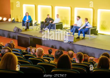 Vue grand angle des réalisateurs donnant une présentation tout en étant assis sur la scène éclairée dans la salle de conférence Banque D'Images