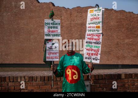 Dhaka, Bangladesh. 14 décembre 2023. Un vieil homme vu tenant des pancartes alors qu'il rend hommage aux intellectuels martyrs. Les Bangladeshis ont rendu hommage aux dizaines d'intellectuels tués pendant la guerre, qui a conduit au succès de l'indépendance du pays d'Asie du Sud vis-à-vis du Pakistan. Les intellectuels ont été systématiquement tués à travers l'ancien Pakistan oriental par l'armée pakistanaise et leurs collaborateurs pour mutiler la nation émergente de son peuple talentueux et intellectuel. (Photo de Sazzad Hossain/SOPA Images/Sipa USA) crédit : SIPA USA/Alamy Live News Banque D'Images