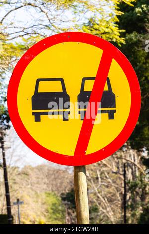 Panneau de signalisation sur poteau avec une illustration d'itinéraire d'instruction de véhicule en peinture noire jaune et rouge. Banque D'Images