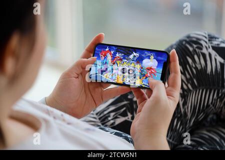 Pokemon GO jeu iOS mobile sur iPhone 15 écran de smartphone dans les mains féminines pendant le jeu mobile. Jeux et divertissements mobiles sur un appareil portable Banque D'Images