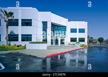 L'invention concerne un bâtiment de construction basculant vers le haut, contrôlé en perspective, situé dans un parc d'activités. Photographié avec un parking humide. Banque D'Images