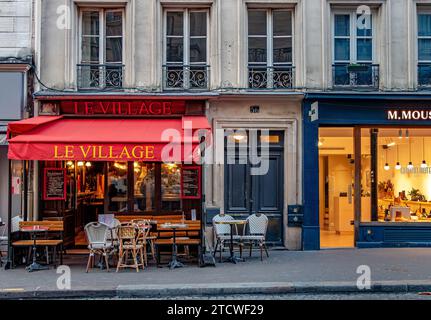 Tables et chaises devant le Village, un petit restaurant, un café rue des Abbesses, Montmartre dans le 18e arrondissement de Paris, France Banque D'Images
