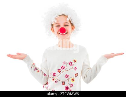 Mignonne adolescente en perruque de clown blanc et grand nez rouge montrant deux paumes vides et regardant la caméra isolée sur fond blanc. CopySpace Banque D'Images