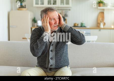 Maux de tête. Malheureux homme âgé d'âge moyen souffrant de maux de tête malade frottant les tempes à la maison. Vieux grand-père aîné mature touchant les temples éprouvant du stress. Homme sentant mal à la tête Banque D'Images