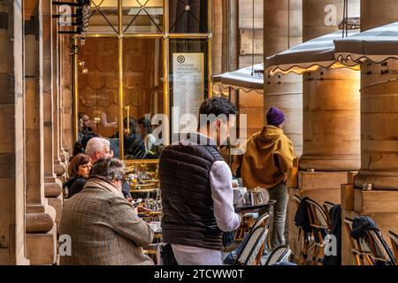 Un serveur servant le thé sur la terrasse du Nemours, une brasserie à la mode avec une terrasse près du Palais Royal, Paris, France Banque D'Images