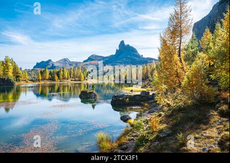 Vue majestueuse sur le lac Federa entouré de mélèzes dorés et de montagnes rocheuses escarpées dans les Dolomites italiennes. Banque D'Images