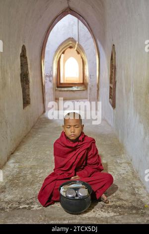 Un moine bouddhiste novice médite à l'intérieur du temple Ananda, Bagan, Myanmar. Banque D'Images