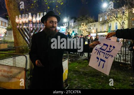 Londres, Royaume-Uni. 14 décembre 2023. Un événement de solidarité auquel ont participé des députés, des dirigeants communautaires et des membres du public a eu lieu après que la menorah a été vandalisée sur Islington Green plus tôt aujourd'hui. Rabbi Mendy Korer a dirigé les débats, reluisant les bougies - et la huitième et dernière pour le festival de Hanukkah. La police métropolitaine enquête et pense que la menorah a été intentionnellement endommagée, car les incidents antisémites augmentent depuis les attaques du Hamas en Israël. Crédit : Photographie de onzième heure / Alamy Live News Banque D'Images