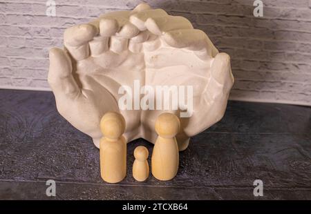 Figurines en bois d'une jeune famille sur un fond blanc. Concept d'un jeune couple marié forte et saine. Un couple aimant s'attend à ce que la naissance d'un Banque D'Images