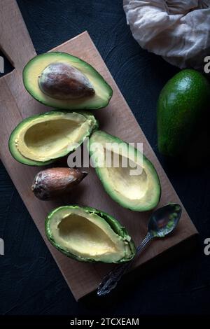 Moitiés d'avocat sur une planche à découper en bois. Avocat demi avec un os. Avocat sur table en bois rustique. Banque D'Images