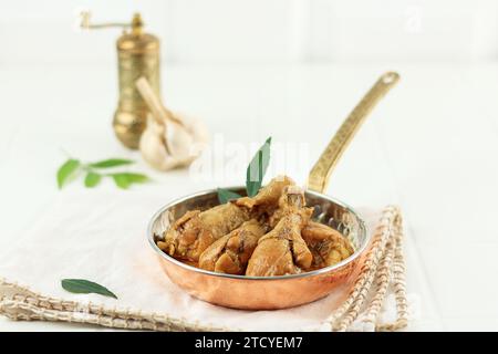 Poulet rougeâtre épicé Curry Masala, avec morceau de jambe proéminent sur la table blanche. Indonésien Kare Ayam Banque D'Images