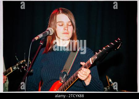 TRISH KEENAN, DIFFUSION, 1996 : a very Young Trish Keenan (1968-2011) la chanteuse du groupe British Electronic Broadcast jouant une guitare Wilson Rapier 44 en soutien à Stereolab Cardiff University, pays de Galles, Royaume-Uni le 21 novembre 1996. Cette photo a été prise au début de la tournée de carrière acclamée par la critique avec leur premier single et leur premier EP, The Book Lovers. Malheureusement, Trish meurt inopinément d'une pneumonie après avoir contracté la grippe porcine en janvier 2011 alors qu'elle était en tournée en Australie. Photo : Rob Watkins Banque D'Images