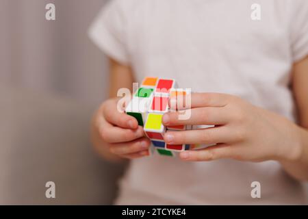 Gros plan du cube coloré de Rubik dans les mains de la petite fille Banque D'Images