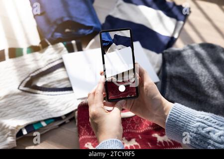 Une femme qui prend une photo et l’enregistre sur une application pour vendre ses biens d’occasion Banque D'Images