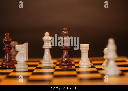 Pièces d'échecs sur une planche en bois sur un fond sombre Banque D'Images
