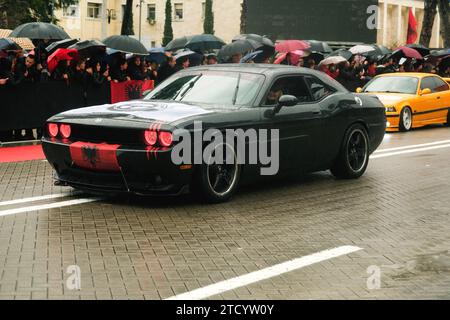 Tirana, Albanie - 28 novembre 2023 : sur l'avenue des Martyrs de la Nation, les citoyens assistent à un défilé de voitures modifiées, dont une Dodge Challenger noire Banque D'Images