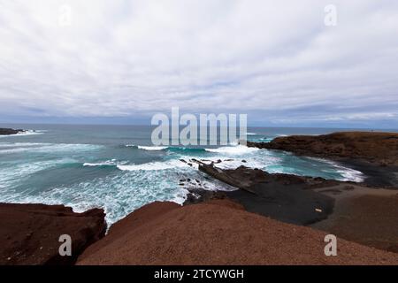 Vue panoramique sur la plage volcanique Playa El Golfo et la côte rocheuse par jour venteux. Vu du point de vue du Charco de los Clicos. Lanzarote, îles Canaries. Banque D'Images