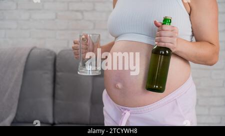 Femme enceinte tenant verre et bouteille de bière. Banque D'Images