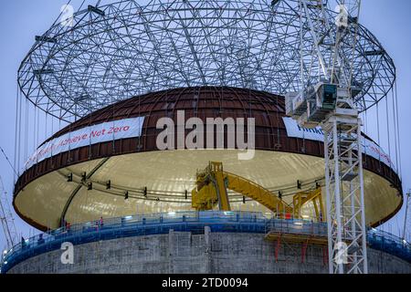 Les équipes d'ingénierie utilisent la plus grande grue du monde, Big Carl, pour soulever un dôme en acier de 245 tonnes sur le premier bâtiment de réacteur de Hinkley point C, sur le site de construction de la centrale nucléaire de Bridgwater, Somerset. Le dôme de 14 mètres de haut est manoeuvré en position au sommet du bâtiment du réacteur de 44 mètres de haut, aux premières heures du vendredi matin. Cette étape importante dans la construction ferme le bâtiment du réacteur, permettant ainsi l’installation du premier réacteur nucléaire à l’intérieur. Date de la photo : Vendredi 15 décembre 2023. Banque D'Images