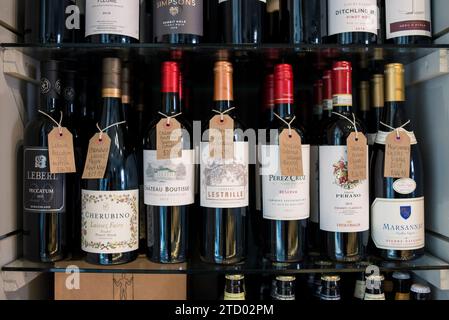 Étagères avec des bouteilles de vin et de gin haut de gamme en vente dans un magasin de traiteur local. Banque D'Images