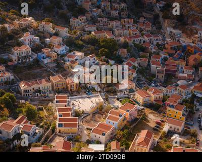 Île de Symi, Grèce - 20 avril 2023 : l'île de Symi est une petite île du Dodécanèse, qui étonne les visiteurs avec une atmosphère calme. Maisons néoclassiques colorées sur les collines de l'île pendant le coucher du soleil. Banque D'Images