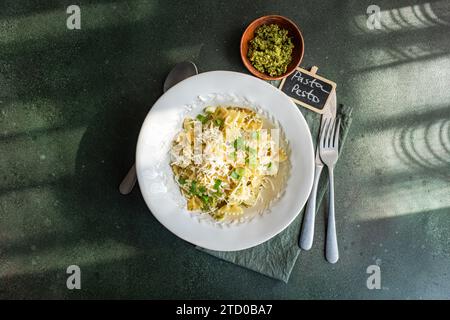 Vue aérienne d'un délicieux plat de pâtes Farfalle recouvert de pesto et de parmesan, servi sur une table élégante. Banque D'Images