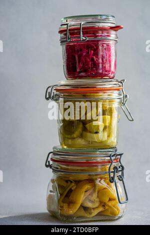 Trois bocaux en verre empilés les uns sur les autres, remplis de légumes fermentés : chou rouge à la betterave, poivrons épicés et concombres blancs Banque D'Images