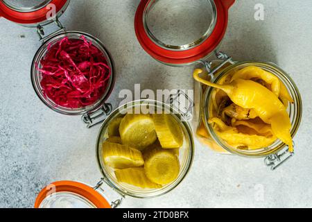 Vue aérienne de bocaux en verre remplis de légumes fermentés colorés, y compris le chou à la betterave, les poivrons épicés et les concombres marinés. Banque D'Images