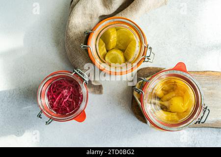 Trois bocaux en verre remplis de légumes fermentés colorés, y compris le chou rose à la betterave, les concombres blancs jaunes et les poivrons épicés, placez Banque D'Images