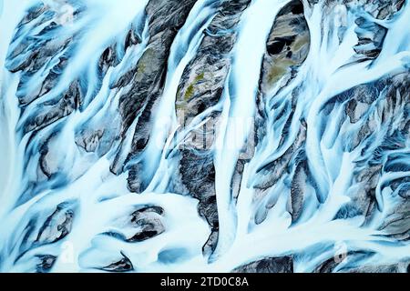 Vue aérienne des bassins fluviaux complexes en Islande, mettant en valeur les magnifiques motifs créés par l'eau qui coule au milieu de la neige Banque D'Images