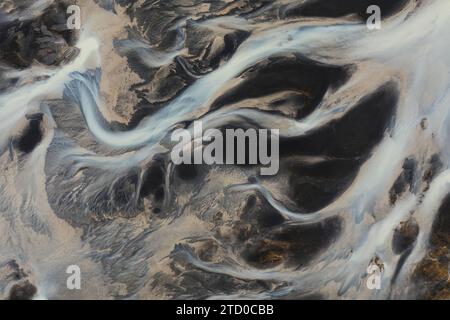Une prise de vue aérienne capturant l'art naturel d'un bassin fluvial islandais avec des motifs complexes de sédiments et d'eau Banque D'Images