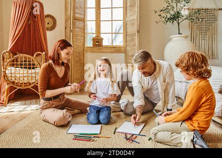 parents souriants et frères et sœurs se rassemblant sur le sol dans un salon moderne, activités créatives Banque D'Images