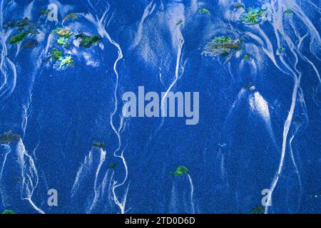 Un gros plan de motifs ondulés abstraits dans le sable bleu créé par les mouvements de marée, avec des taches d'algues vertes sur la côte occidentale des Asturies dans le sud Banque D'Images