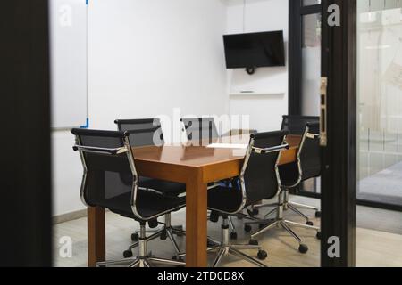 Intérieur de la salle de conférence avec des chaises disposées autour de la table en bois dans le bureau créatif vide vu par la porte Banque D'Images