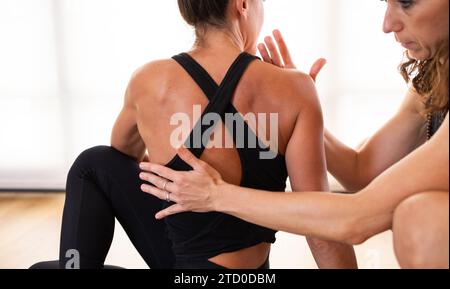 Un instructeur de yoga corrige la posture d'une étudiante dans un studio intérieur Banque D'Images