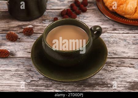 Une tasse de café crémeux sur une table en bois rustique avec des collations. Banque D'Images