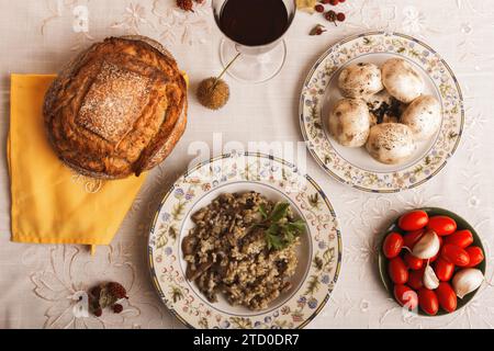 Une vue de haut en bas d'une configuration de repas rustique avec du pain maison, risotto aux champignons et légumes frais. Banque D'Images