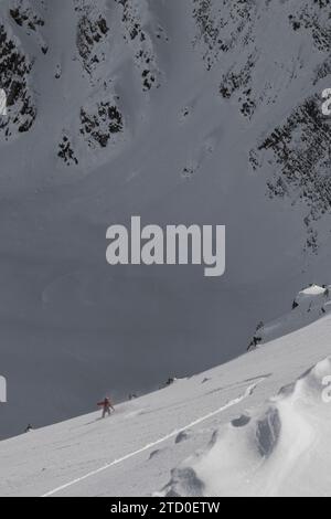 Vue de dessus d'un snowboardeur anonyme descendant sur une majestueuse pente de montagne enneigée contre un ciel bleu clair tout en profitant de vacances d'hiver au Canada Banque D'Images